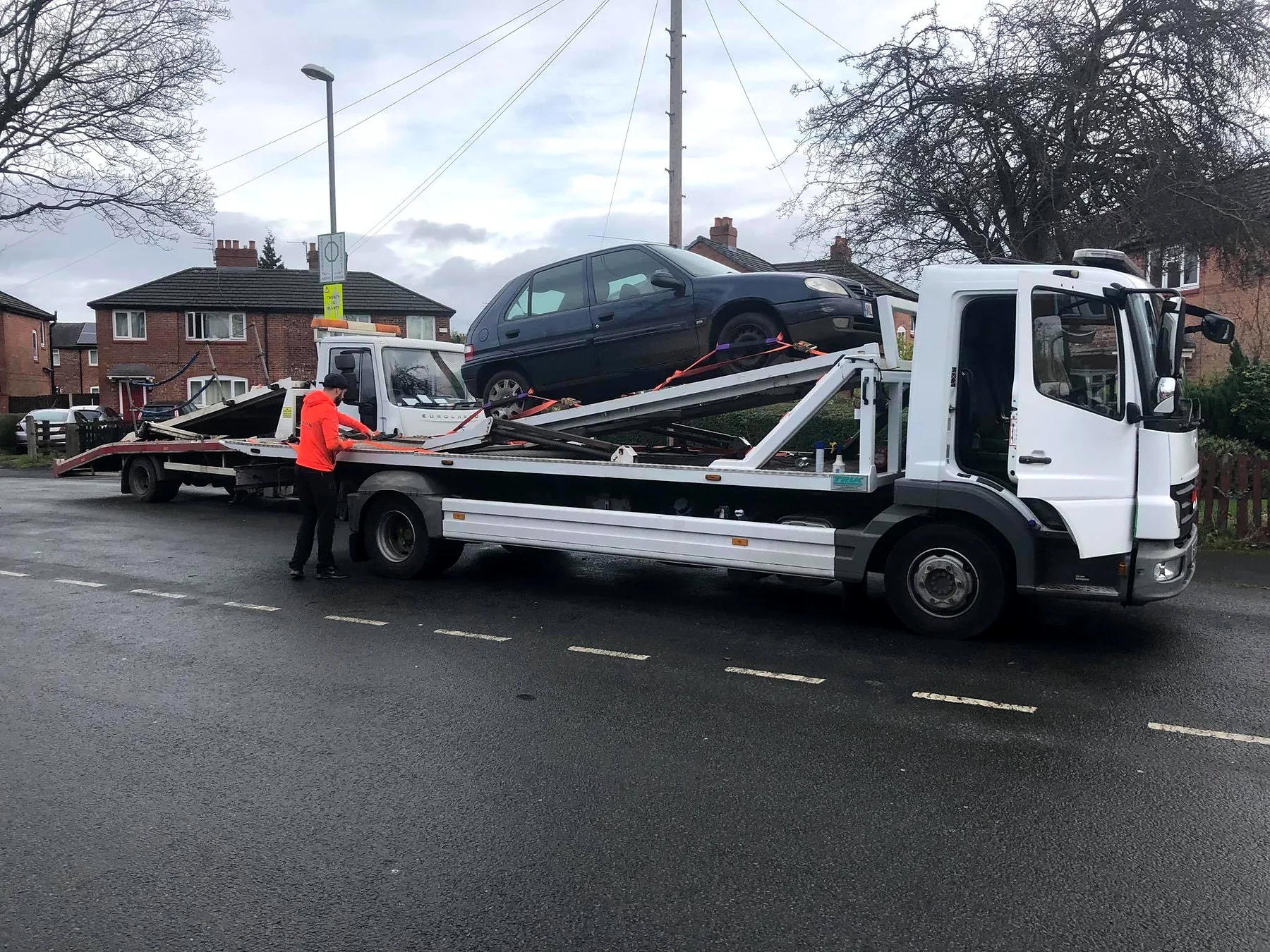 Car loaded using recovery equipment on a residential street