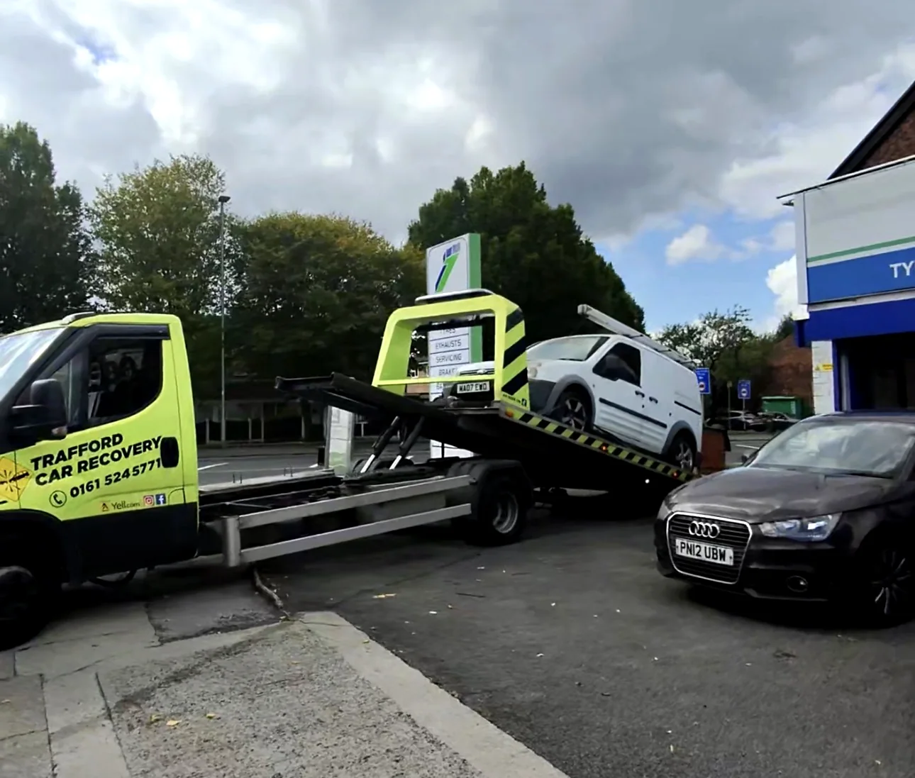 Small white van on a tilted recovery bed