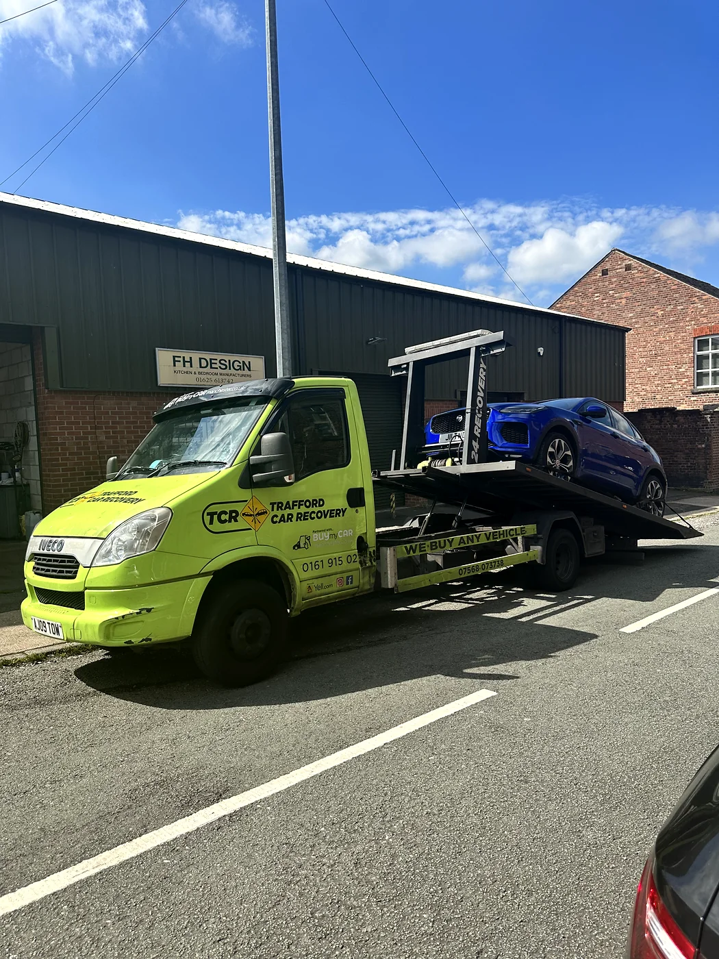 Blue SUV on a recovery truck outside industrial units
