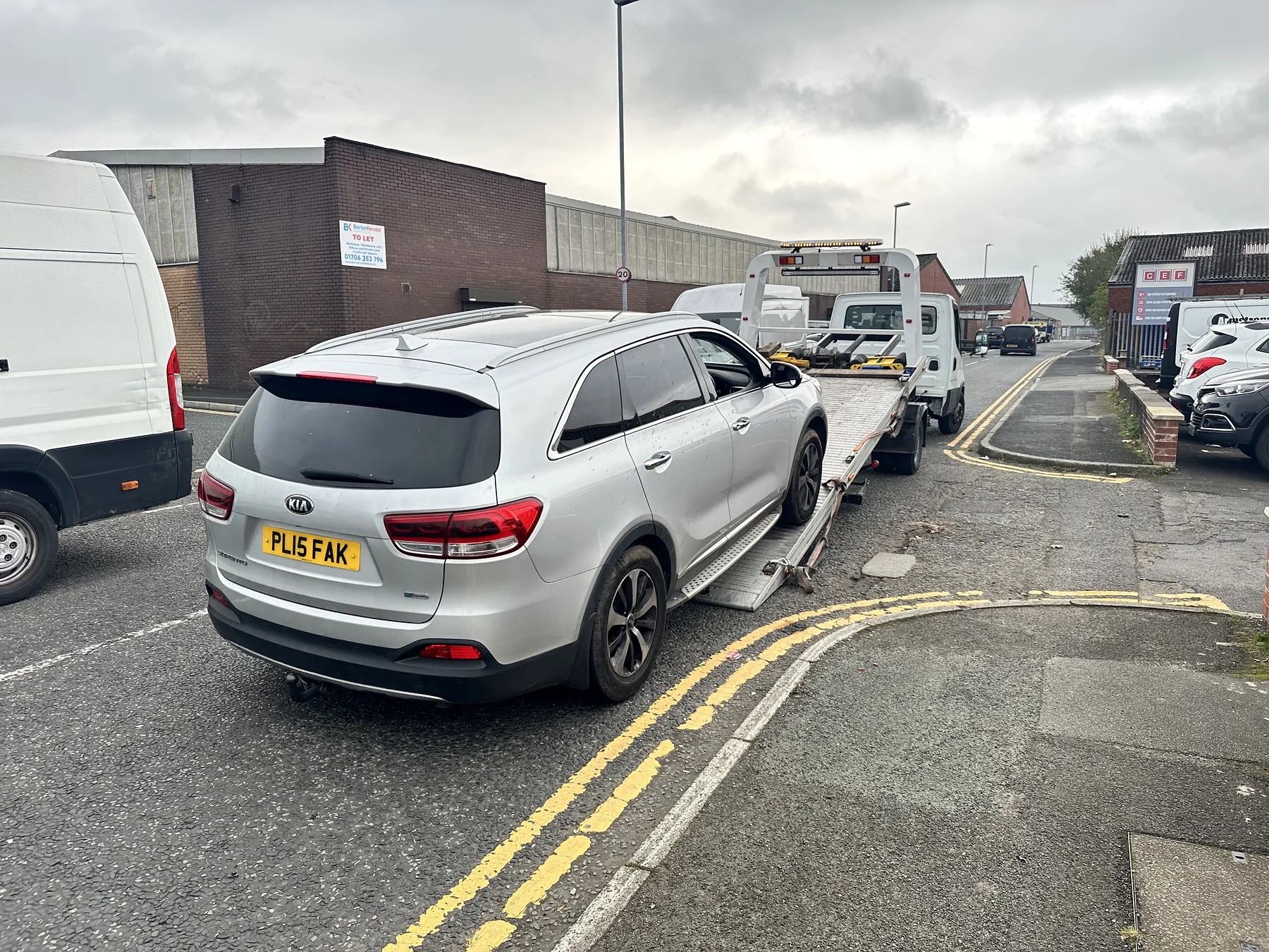 Silver SUV being loaded beside an industrial road