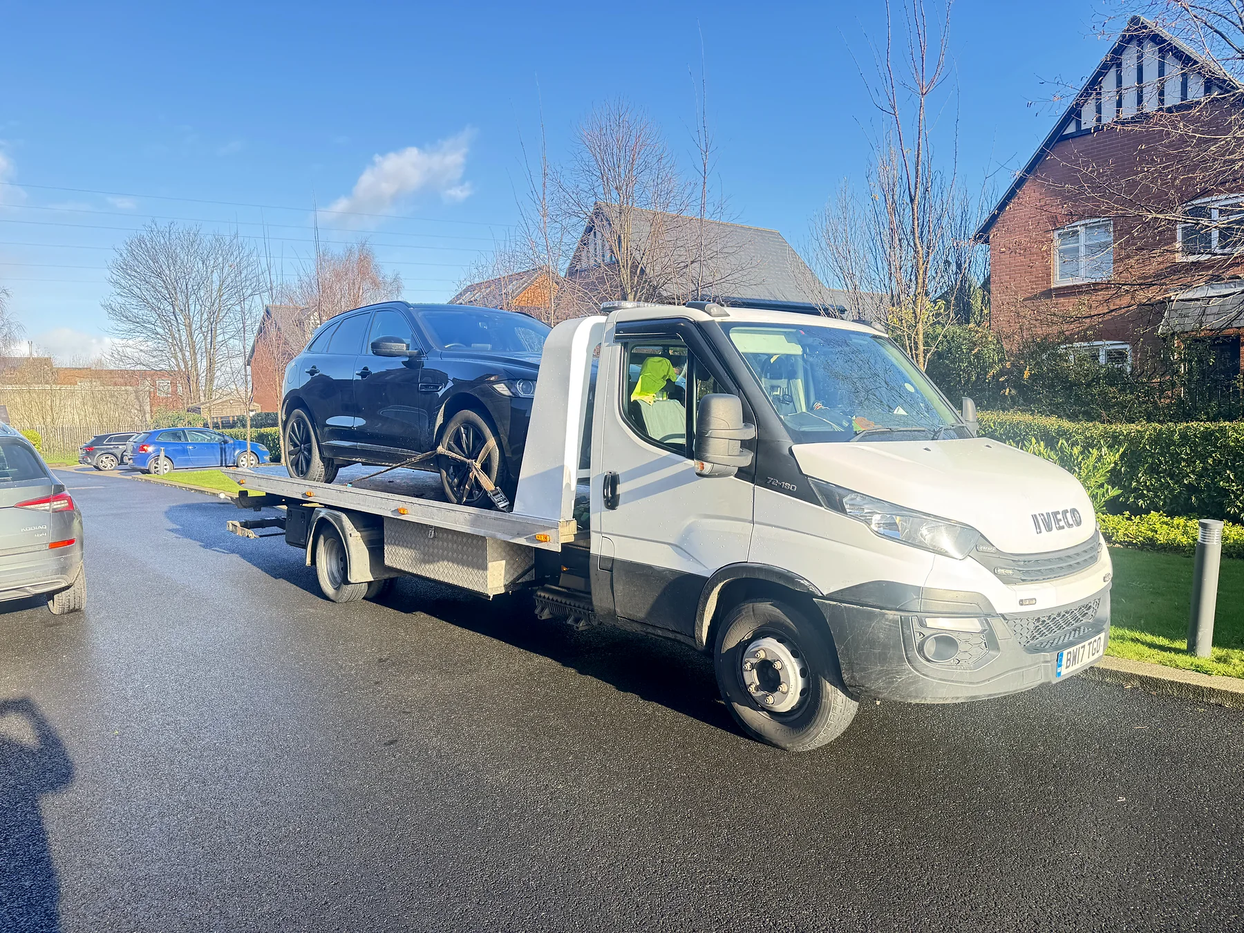 White Iveco recovery truck carrying a dark SUV