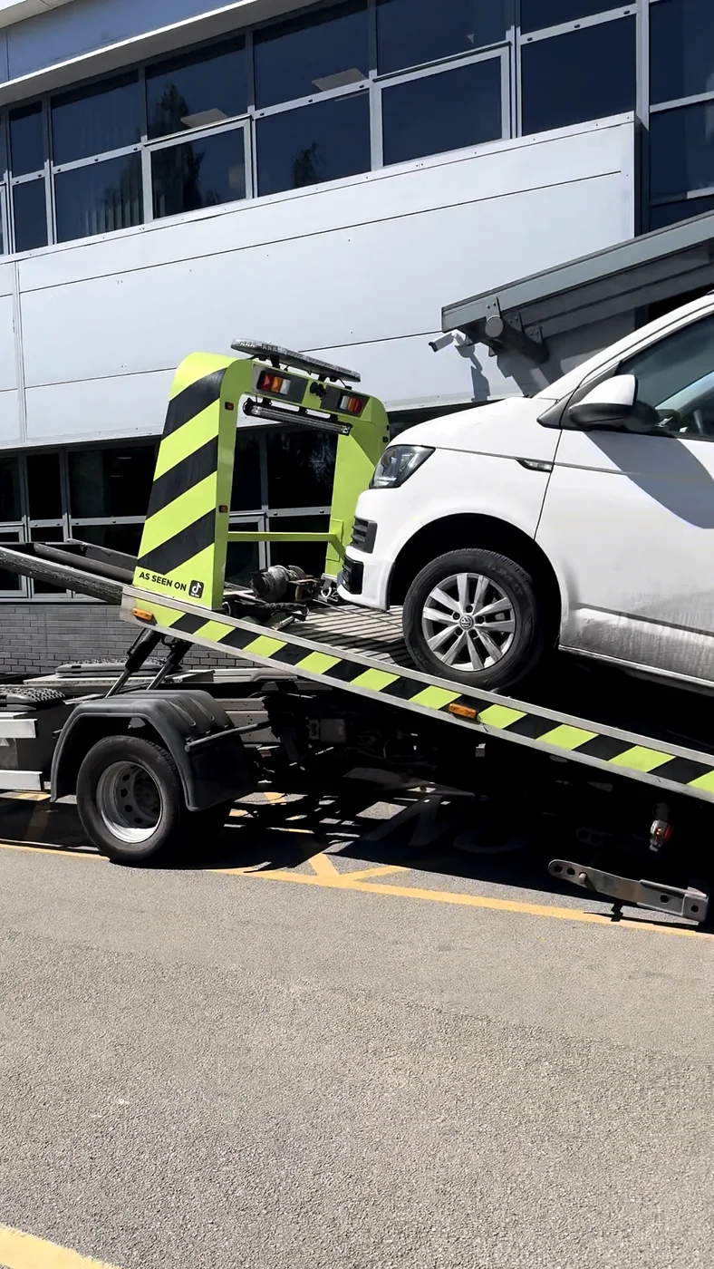 White van on a tilted recovery bed outside industrial units