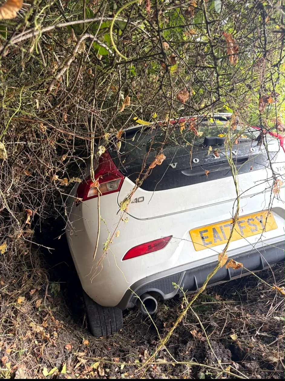 White car off the road in a hedge