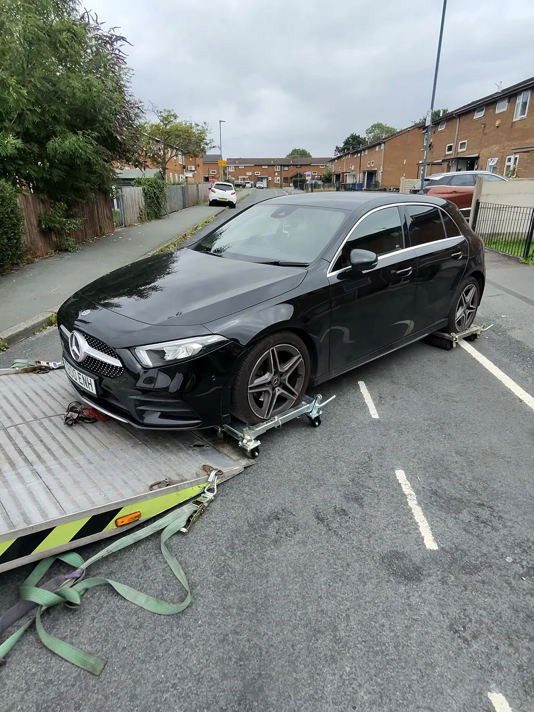 Black Mercedes supported by wheel skates beside a recovery ramp